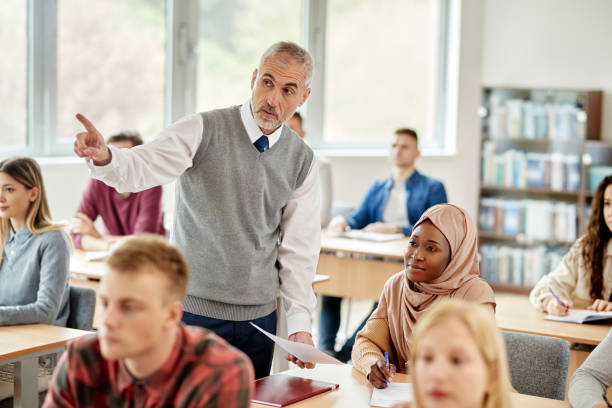 Senior university professor explaining something to African American Muslim student during a class in the classroom.